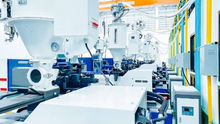 Moderni macchinari e attrezzature industriali in una fabbrica ben illuminata, con tubi, pannelli di controllo e macchinari automatizzati.
