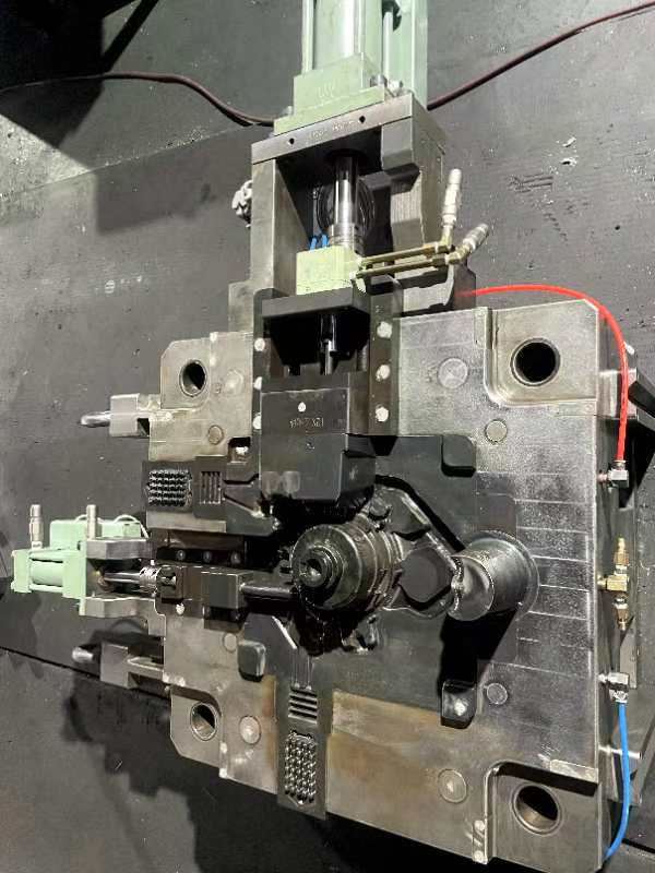 Prim-plan al unor utilaje industriale cu componente metalice, șuruburi și țevi pe o suprafață întunecată.