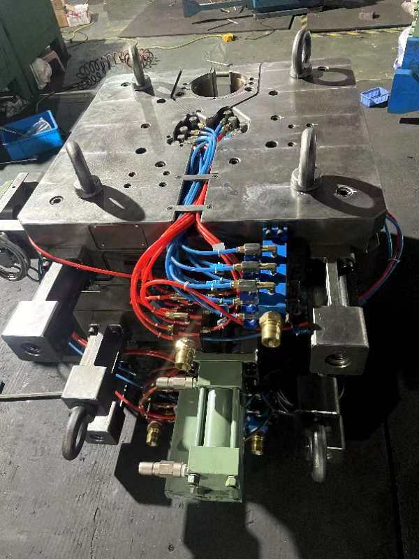 Ein Maschinenteil aus Metall mit Kabeln und Schläuchen auf dem Werkstattboden.