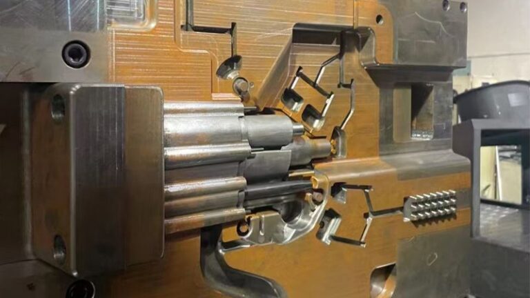 Gros plan d'un moule métallique industriel avec des motifs et des canaux complexes, faisant partie d'une machine plus grande.