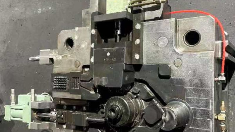 Close-up of industrial machinery featuring metal components, bolts, and pipes on a dark surface.