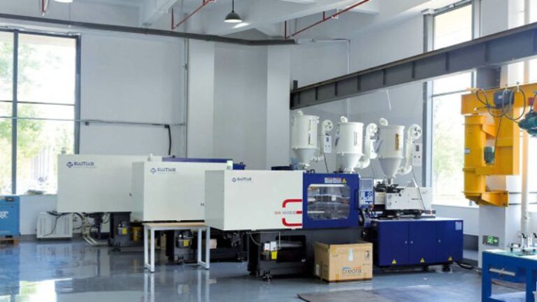 Machines de moulage par injection plastique dans une installation lumineuse avec de grandes fenêtres et des équipements suspendus.