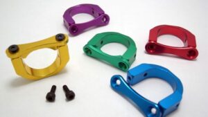 Cinq pinces colorées (jaune, violet, vert, rouge, bleu) et deux vis sur fond blanc.