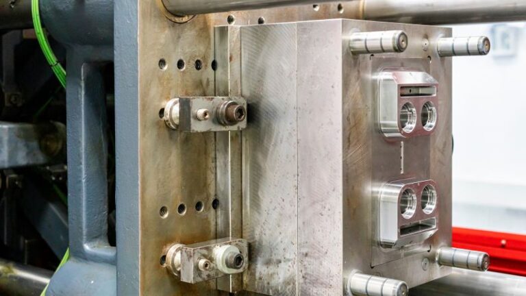 Gros plan d'un moule métallique industriel détaillé fixé avec des boulons dans une machine.