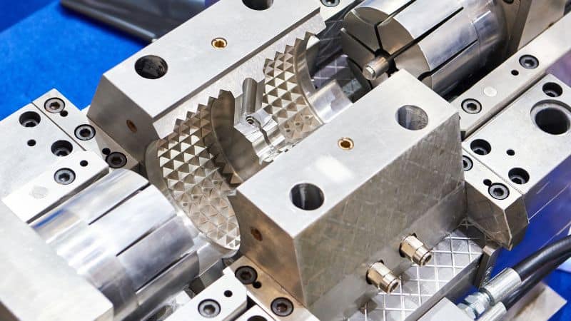 Close-up of a precision metal mold with textured and smooth surfaces, used to shape materials in manufacturing.