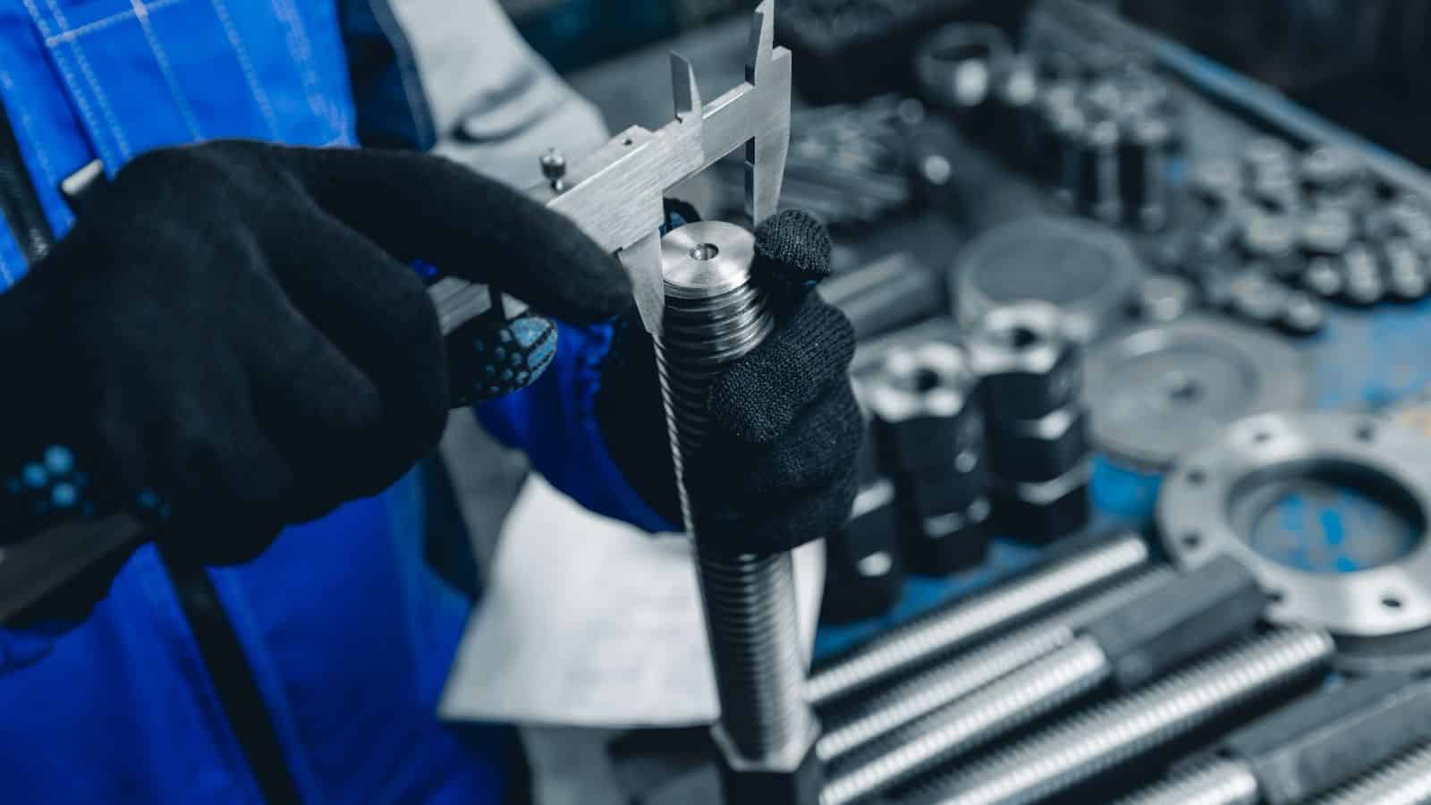 a worker measuring a metal part for quality control