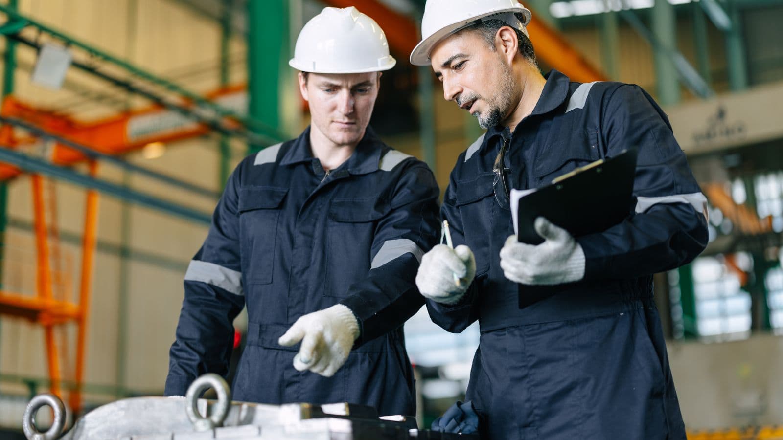 Two engineers in safety helmets inspecting metal castings in a manufacturing plant, emphasizing quality control in die casting processes.