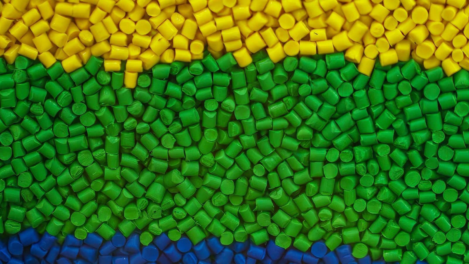 Close-up of colorful plastic pellets used in injection molding for packaging solutions, showcasing the material's versatility and quality.