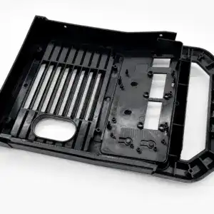 Injection mold for automotive control panel, black plastic component with detailed cavities and mounting points.