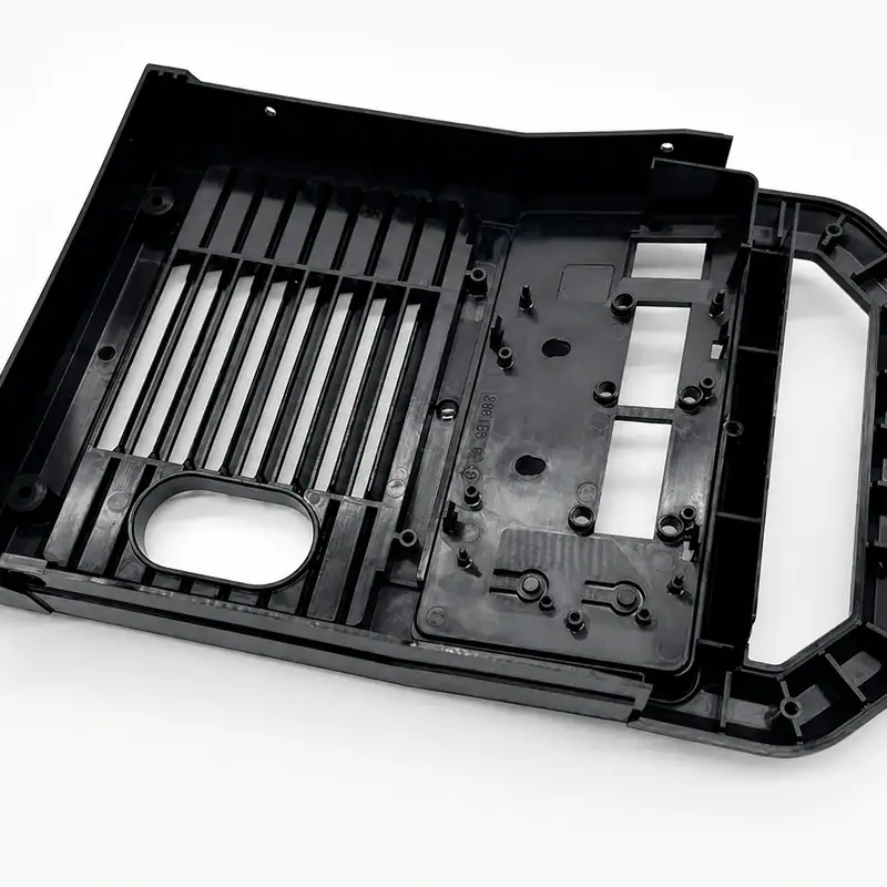 Injection mold for automotive control panel, black plastic component with detailed cavities and mounting points.